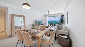 Un área de comedor moderna con vista al océano, un sofá y un televisor.