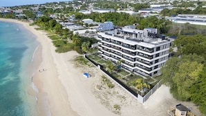 Un hotel moderno de varios pisos con piscina en la azotea, situado junto a la playa.