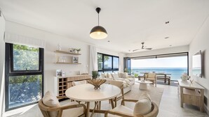 A modern living room with a round table, sofas, and a view of the ocean.