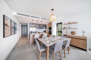 A modern kitchen with a central island, pendant lighting, and a dining area with a table set for four. - Allure 501 3 Bedroom Apts (Bridgetown)