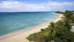 Une plage aux eaux turquoise et limpides, bordée d’un rivage sablonneux et d’une végétation luxuriante.
