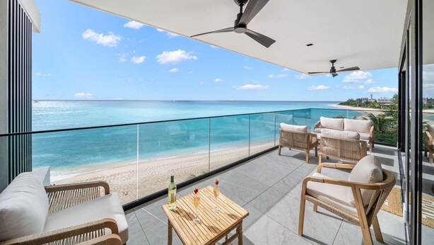 A balcony with a view of the ocean, wicker furniture, and a ceiling fan. - Allure 505 3 Bedroom Apts (Bridgetown)