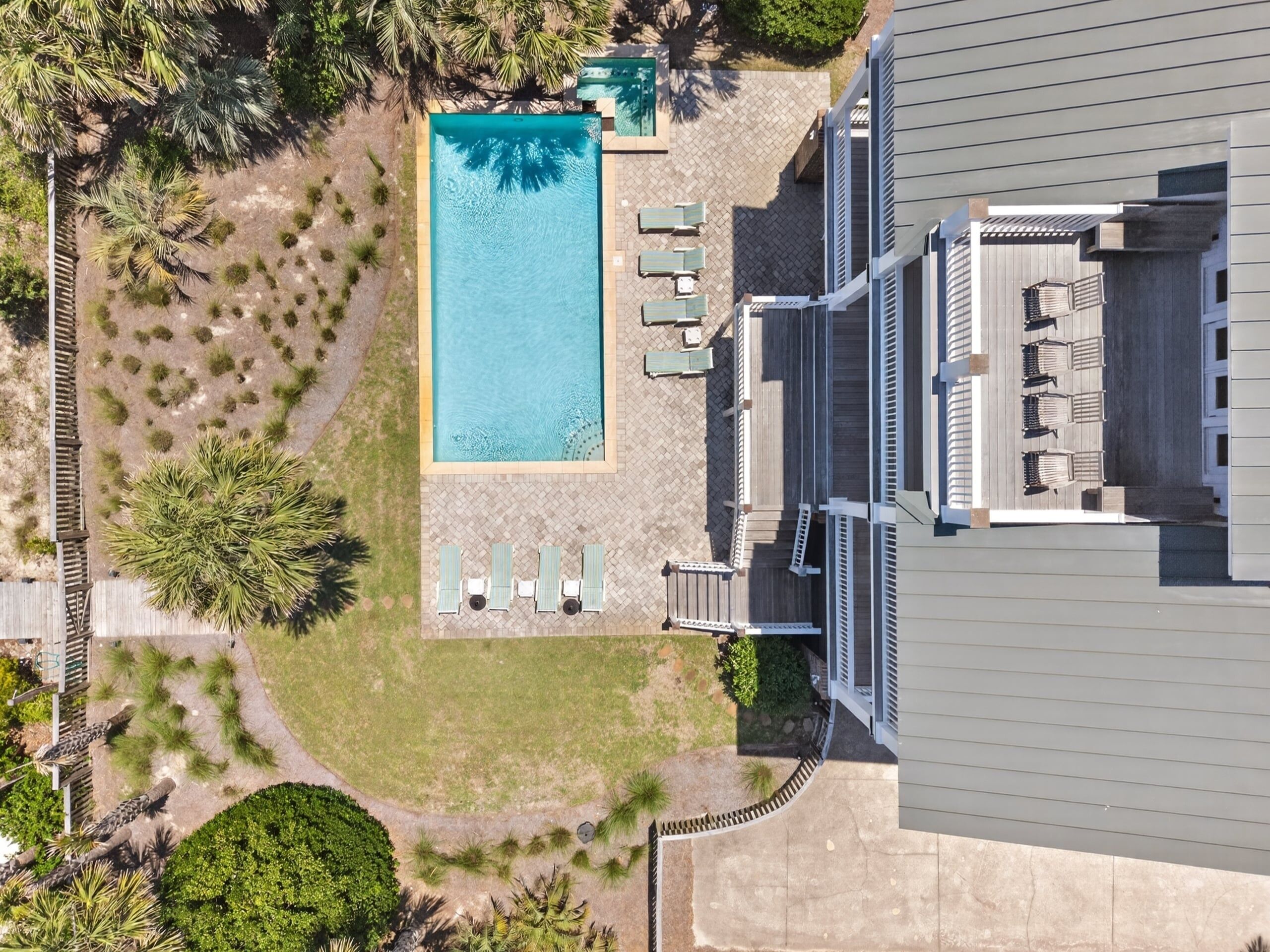 Vue aérienne d’un hôtel doté d’une piscine, de chaises longues et d’un jardin aménagé.