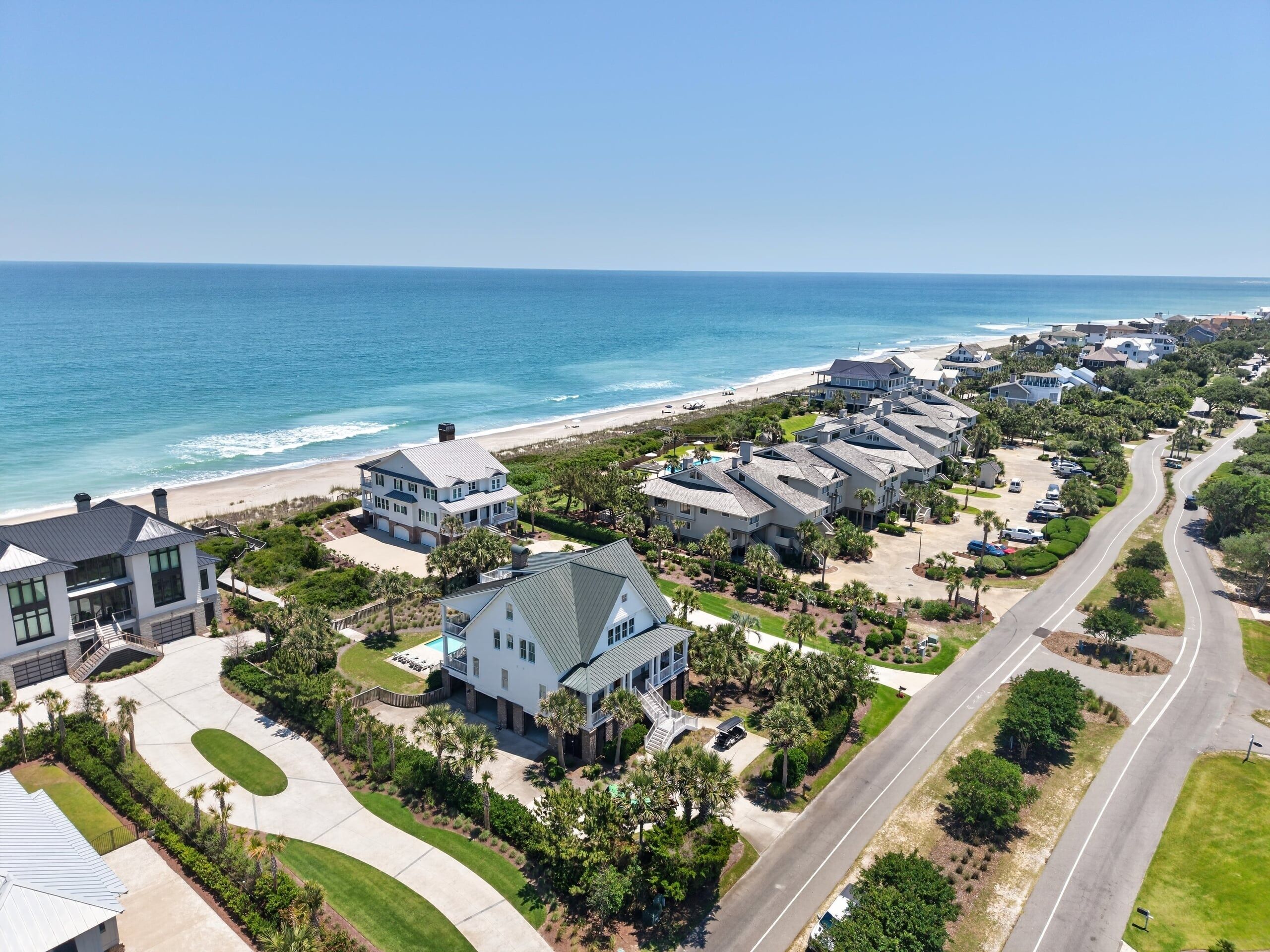 A coastal residential area with houses, a beach, and a clear sky.