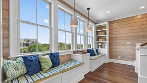 A room with large windows, built-in seating, wooden floors, and a white wall with shelves. - Sun And Solitude 7 Bedroom Home (Georgetown)