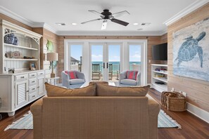 A living room with a sofa, two armchairs, a TV, and a painting of a turtle.