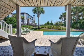 Eine überdachte Terrasse mit Korbmöbeln und einem Pool.