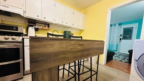A kitchen with white cabinets, a wooden island, and a washing machine. - Charming 2-bedroom house in Aberdeen with WiFi and AC (Aberdeen)