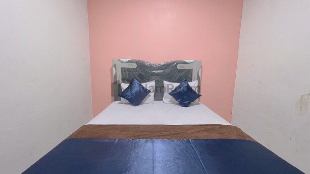 Een kamer met een bed, een roze muur en een houten hoofdbord.