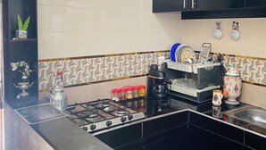 A kitchen with black cabinets, a gas stove, a window, and decorative items on shelves. - Apartment in the center of Tiznit (tiznit neuf)