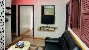A living room with a black leather sofa, a small coffee table, a TV mounted on the wall, and a red neon light strip. - Apartment in the center of Tiznit (tiznit neuf)