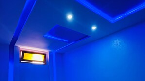 A bedroom with a wooden bed, a small window, and blue ambient lighting. - Apartment in the center of Tiznit (tiznit neuf)