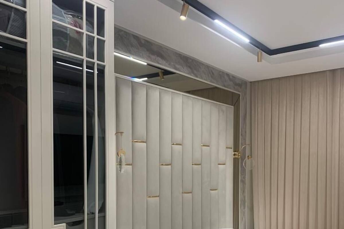 A bedroom with a bed, a wardrobe with glass doors, and a bedside table.