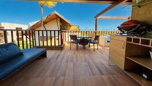 A wooden deck with a sofa, dining table, chairs, and a grill area. - Porto de Galinhas, Malawi Beach Resort - Flat SKY (Ipojuca)