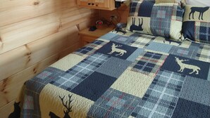 Une chambre confortable dans un chalet, avec un lit, une armoire en bois, un climatiseur fixé au mur, un tableau encadré et une fenêtre.