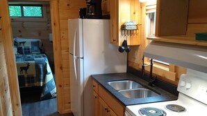 Une cuisine de taille réduite, dotée de meubles de rangement en bois, d’un réfrigérateur, d’une cuisinière et d’un évier.