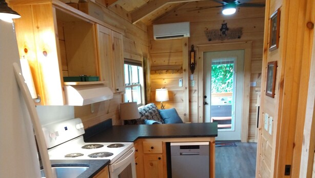 Une cuisine de taille réduite, dotée de meubles de rangement en bois, d’une cuisinière, d’un lave-vaisselle et d’un plan de travail.