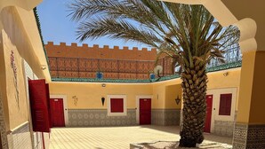 A courtyard with a palm tree, tiled floor, and red doors. - Riad El Borj (Sidi Ahmed Ou Amar)