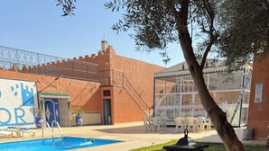 A poolside area with a tiled table and a lantern, surrounded by a brick building and a tree. - Riad El Borj (Sidi Ahmed Ou Amar)