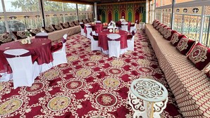 A tented outdoor event space with round tables, white chairs, and a patterned carpet. - Riad El Borj (Sidi Ahmed Ou Amar)
