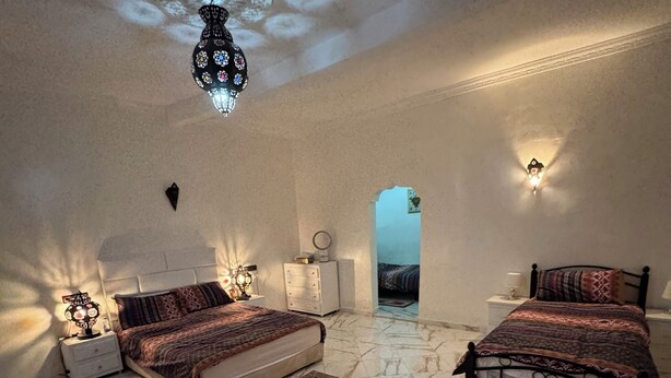 A bedroom with two beds, marble flooring, and a chandelier. - Riad El Borj (Sidi Ahmed Ou Amar)