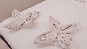 Two towels tied in a bow shape on a white surface. - Hotel Zeke Avenue (Bengaluru)