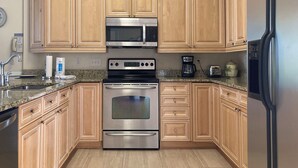 Eine Küche mit Holzausstattung, Edelstahlgeräten, Granitarbeitsplatten und einem eingebauten Backofen.