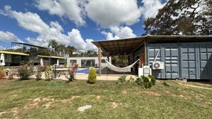 A building with a covered patio, a hammock, and a pool area. - Villela House at Villela Home Stay (Lago Sul)