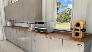 A modern kitchen with light grey cabinets, a wooden countertop, and a built-in wine cooler. - Villela House at Villela Home Stay (Lago Sul)
