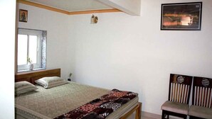 Een slaapkamer met een bed, een raam, een stoel en een aan de muur hangend schilderij.
