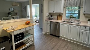 Una cocina moderna con armarios blancos, lavavajillas de acero inoxidable y encimera de madera.