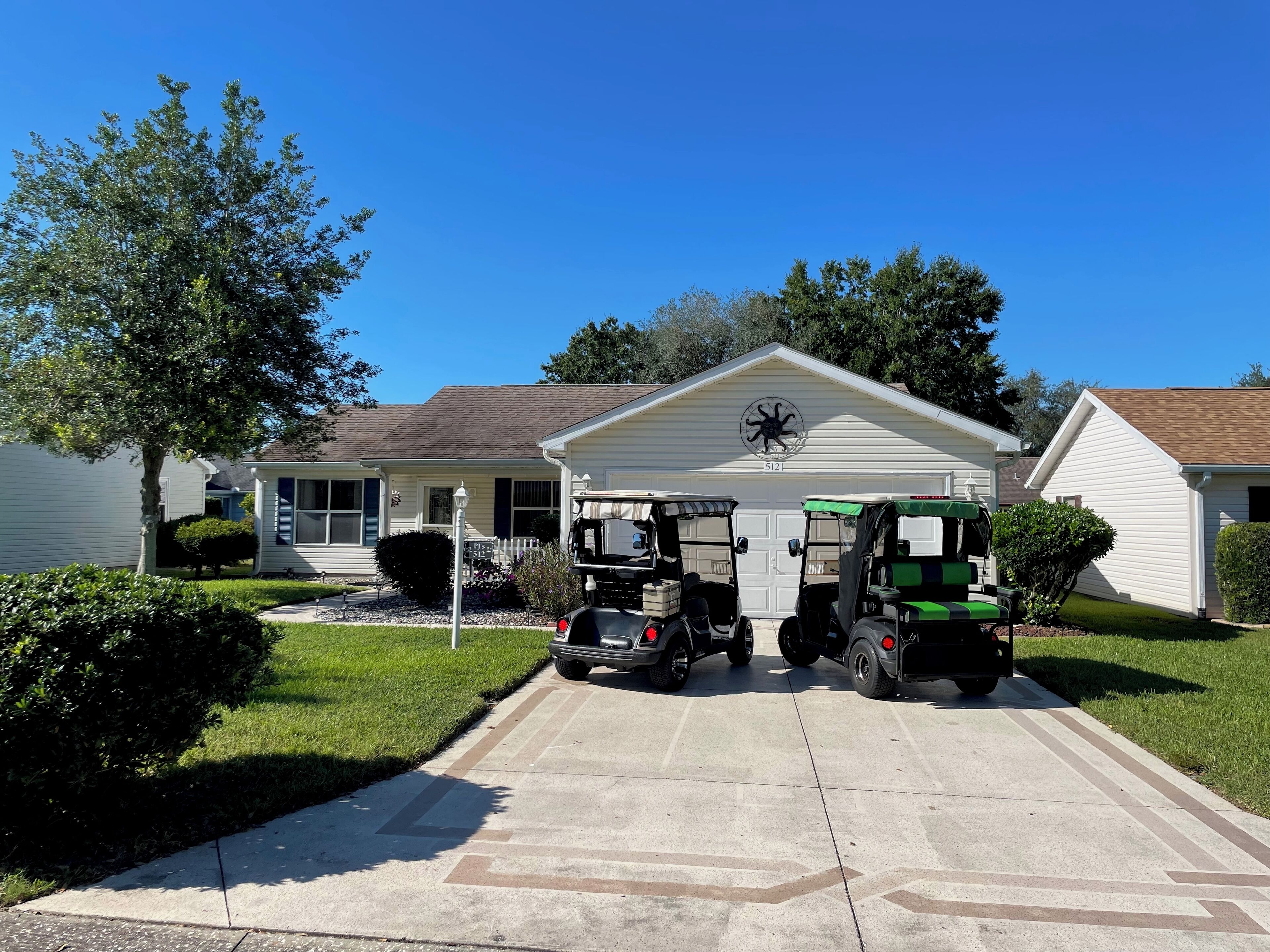 A driveway with two utility vehicles parked in front of a house with a garage.