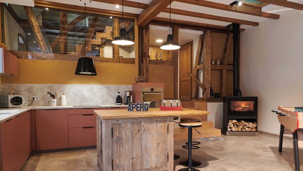Una cocina con vigas de madera, una isla central, una estufa y una mesa de fútbol de mesa.