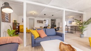 A spacious living area with a sofa, a coffee table, and a dining area in the background. - 5 Star Holiday Home in Hjorring (Hjørring)