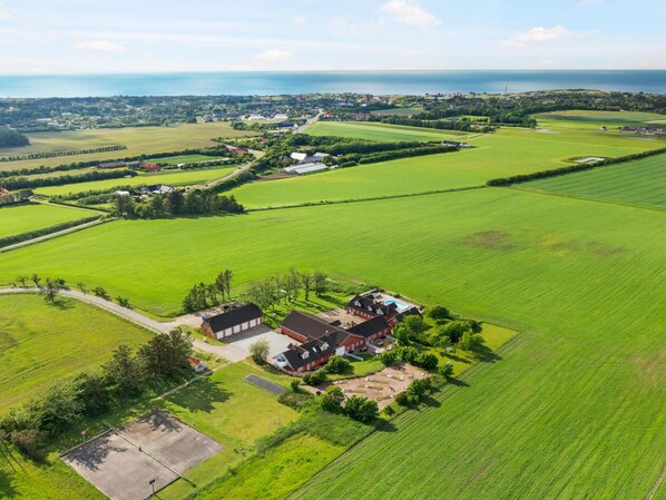 A rural property with a large green field, a red house, and a view of the sea. - 5 Star Holiday Home in Hjorring (Hjørring)