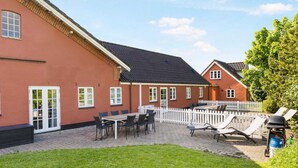 A red building with a white picket fence, a paved patio, and outdoor seating. - 5 Star Holiday Home in Hjorring (Hjørring)