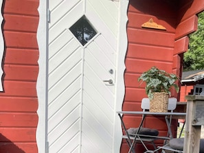 Guesthouse entrance with a distinctive diamond-shaped window and a welcoming potted plant.