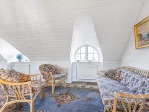 Une chambre à coucher de style loft avec un plafond haut, une grande fenêtre et un canapé en rotin.