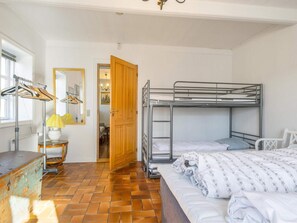 A room with a bunk bed, a wooden door, a radiator, a lamp, and a mirror. - 5 Star Holiday Home in Blokhus (Blokhus)