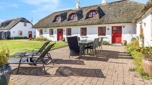 A traditional thatched-roof house with a white exterior and red doors and windows. - 5 Star Holiday Home in Blokhus (Blokhus)