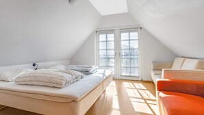 A bedroom with a bed, a chair, and a window with blinds. - 5 Star Holiday Home in Blokhus (Blokhus)