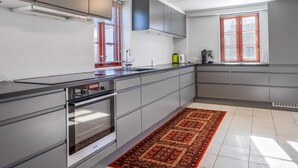 A modern kitchen with grey cabinets, a built-in oven, a sink, and a window with blinds. - 5 Star Holiday Home in Blokhus (Blokhus)