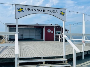 A wooden pier leading to a red building with a sign reading 'BRÄNNÖ BRYGGA'. - 4 Star Holiday Home in Branno (Branno)