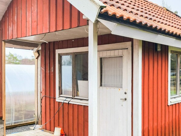 Een rood gebouw met een witte deur en ramen, een pannendak en een overdekte veranda.