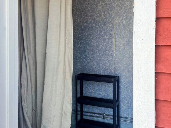 A room with a grey curtain, a blue textured wall, and a black shelf unit. - 4 Person Holiday Park Home in Vaxholm (Vaxholm)