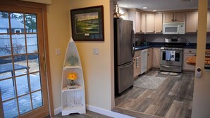 Una cocina con suelo de madera, un refrigerador, un microondas, una estufa y un lavabo.