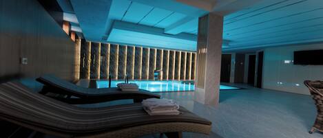 Una piscina techada, una piscina al aire libre de temporada, sombrillas