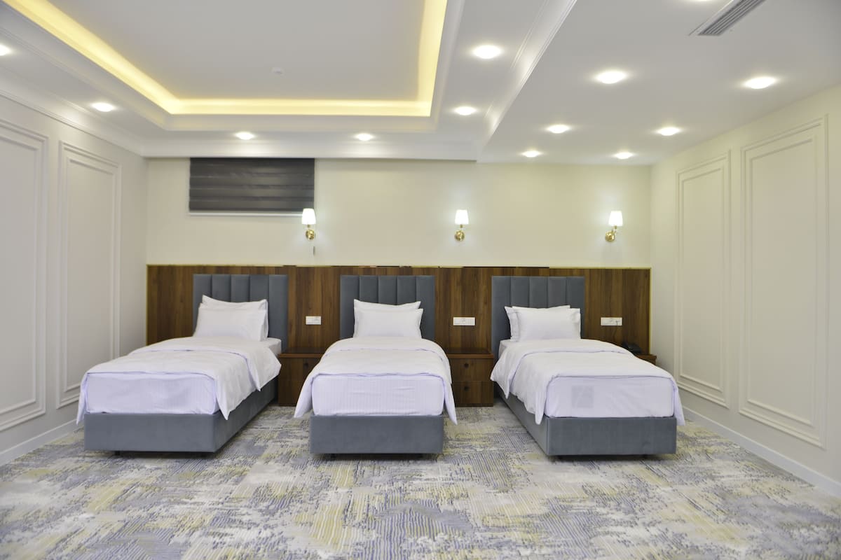 A hotel room with three beds, a wooden headboard, and a patterned carpet.