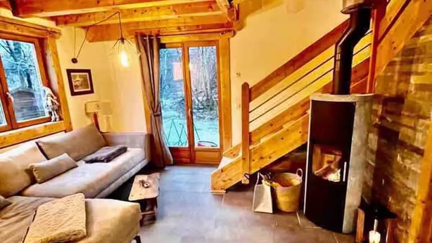 A cozy living room with a sofa, a fireplace, and a staircase leading to an upper level. - Cosy chalet at the foot of the bossons glacier opposite the ski shuttles (Chamonix-Mont-Blanc)
