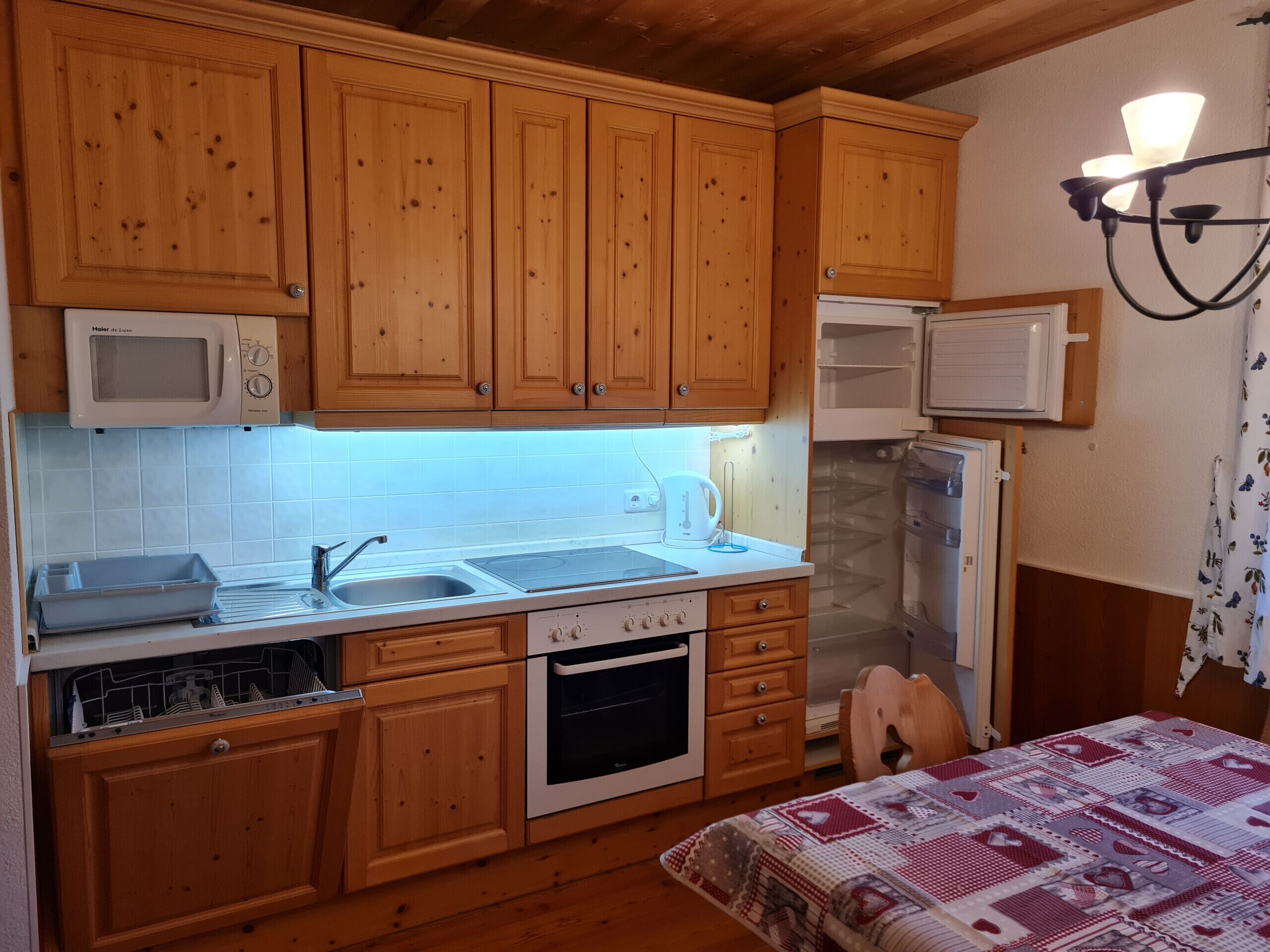 Uma cozinha compacta com armários de madeira, micro-ondas, pia, fogão e geladeira.